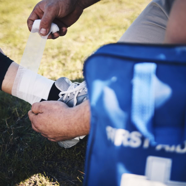 A medical professional is wrapping a patients ankle with a bandage representing delivering medical supplies by drone