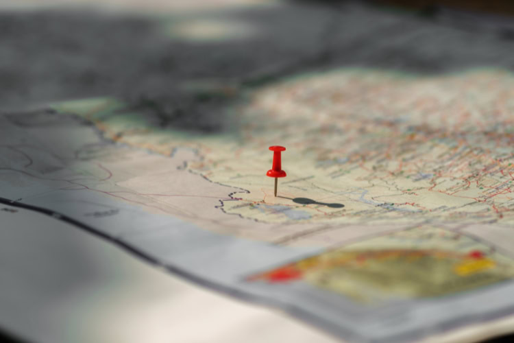 Red push pin marking a location on a paper map